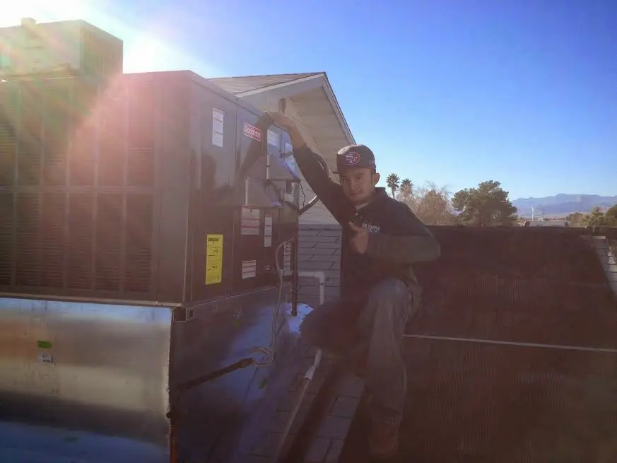 HVAC technician performing AC Tune-Up on a rooftop unit in Bondurant